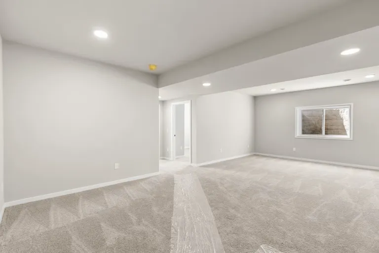 Finished lower-level living space with a full-size window in a representative Wild Oak ranch interior