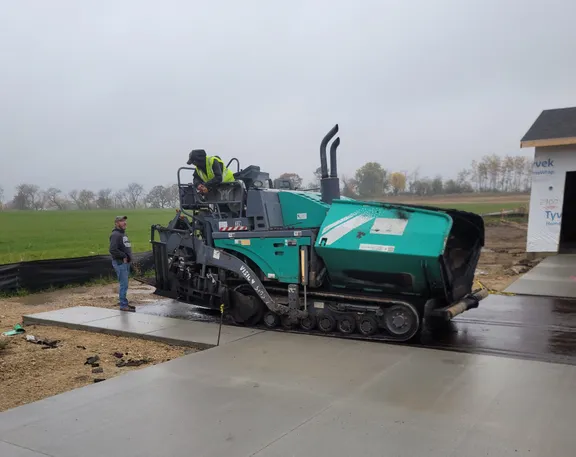 Fresh asphalt topcoat being installed on a Phase 1 road
